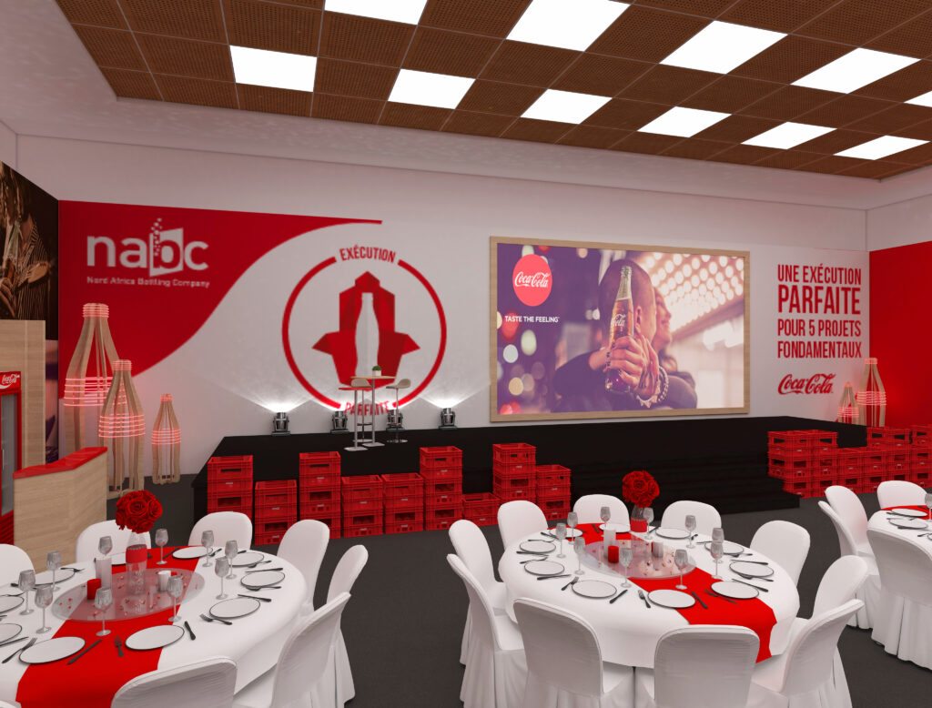 Scène d'un événement corporatif NABC décoré aux couleurs de Coca-Cola, avec des caisses rouges, un écran projetant une publicité Coca-Cola, et des tables dressées en blanc et rouge pour une ambiance immersive, design par Archigram