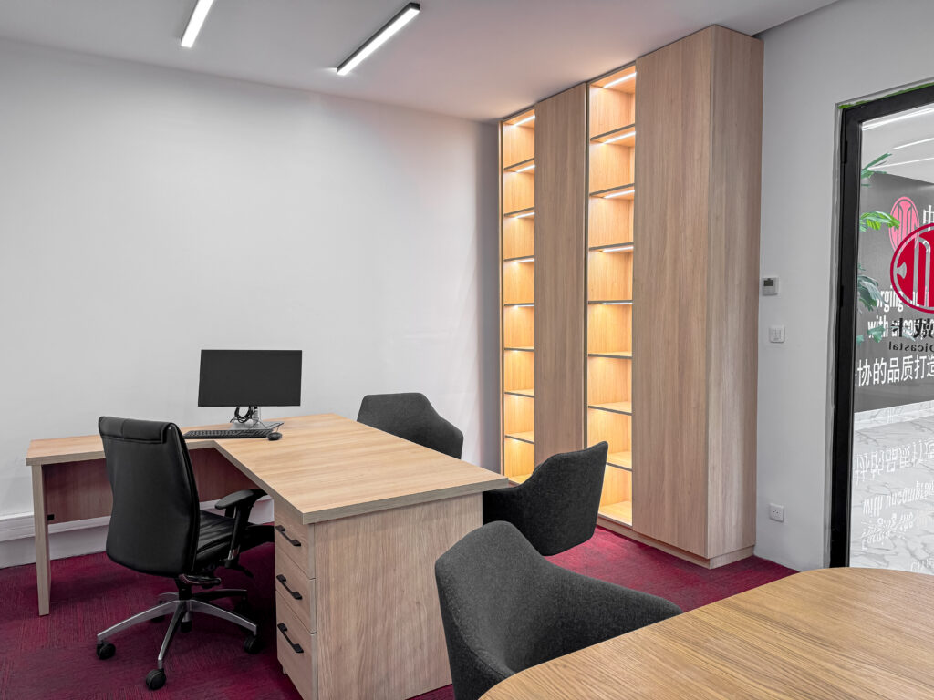 Bureau moderne avec mobilier ergonomique, étagères rétroéclairées et moquette rouge.